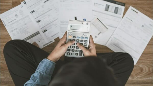 Persona revisando gastos en una libreta con calculadora